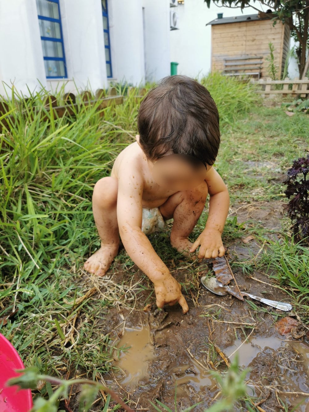 Uma criança a brinca no exterior com lama.